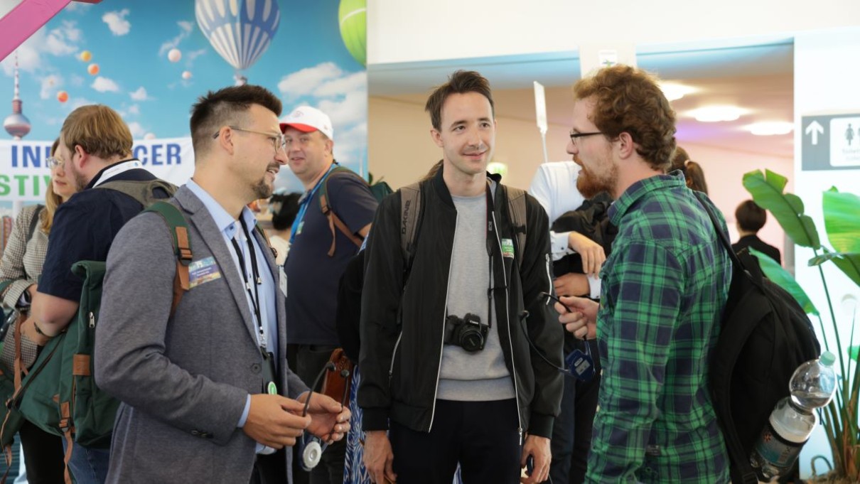 Drei Männer stehen auf dem Railway Influencer Festival zusammen und unterhalten sich.